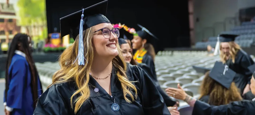 Bachelor student smiling during commencement ceremony.